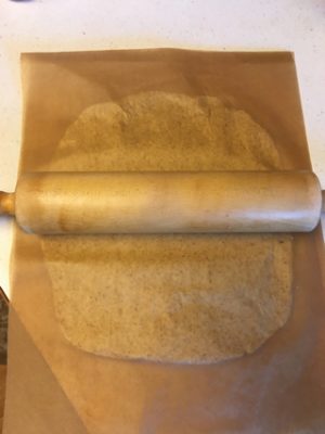 rolling out cassava cracker dough between parchment paper